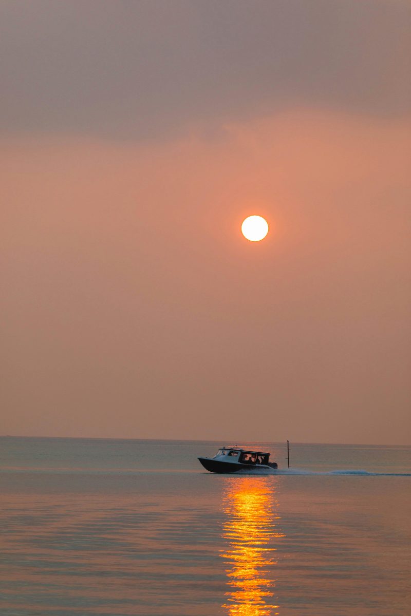 A speedboat silhouetted against a golden sunset off the coast of Koh Samui