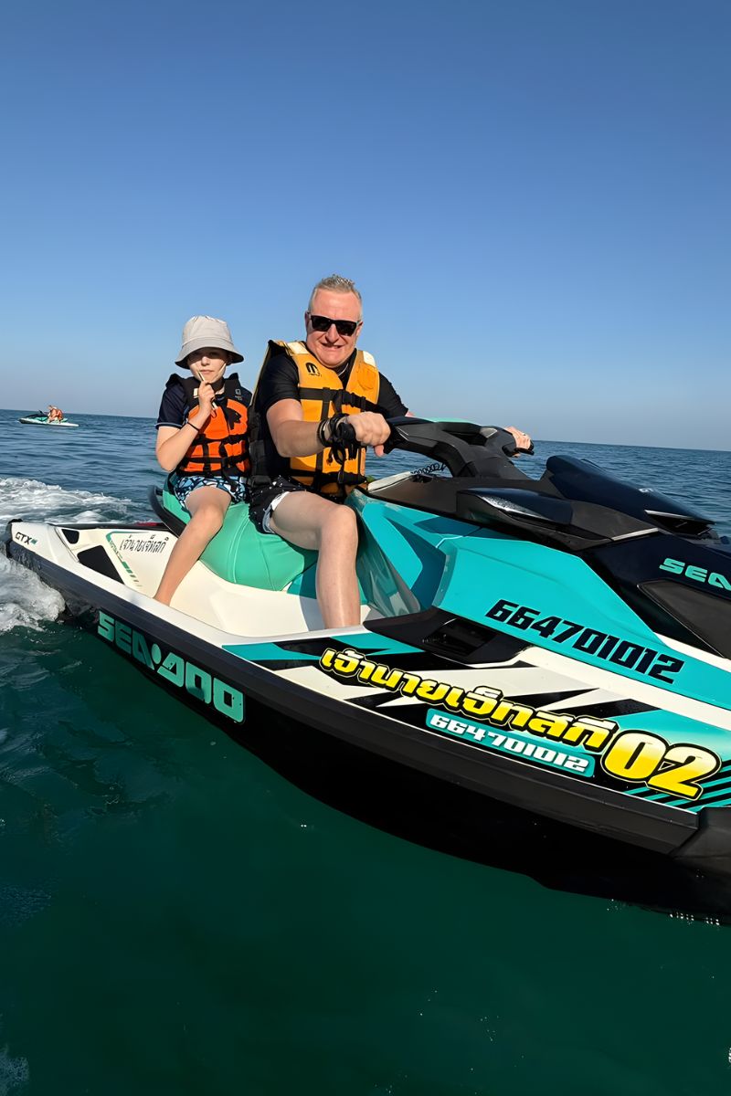Two people on a Seadoo watercraft in the ocean with clear blue sky.