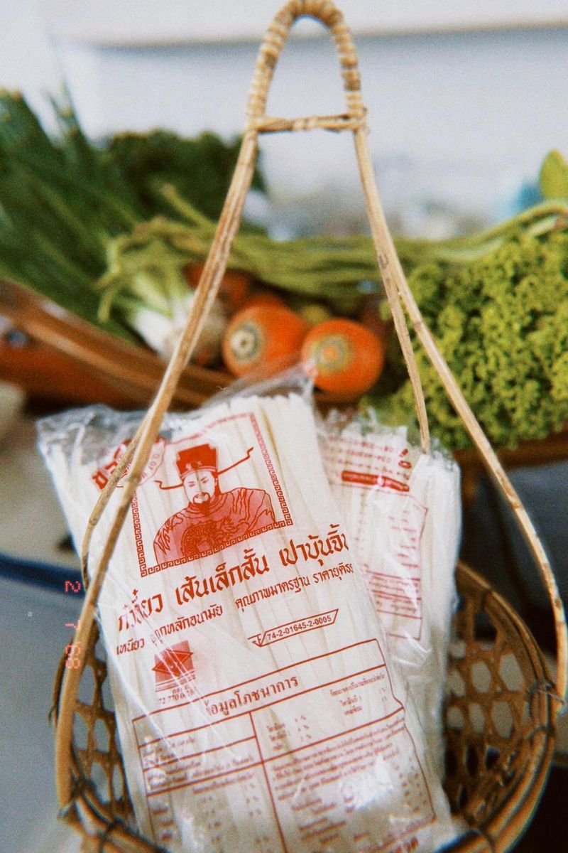 Packages with red and white labels in a woven basket with vegetables in the background