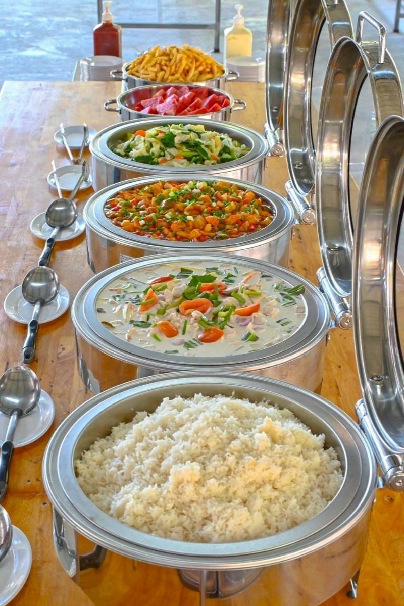 Metallic food serving trays with various dishes on a wooden table.
