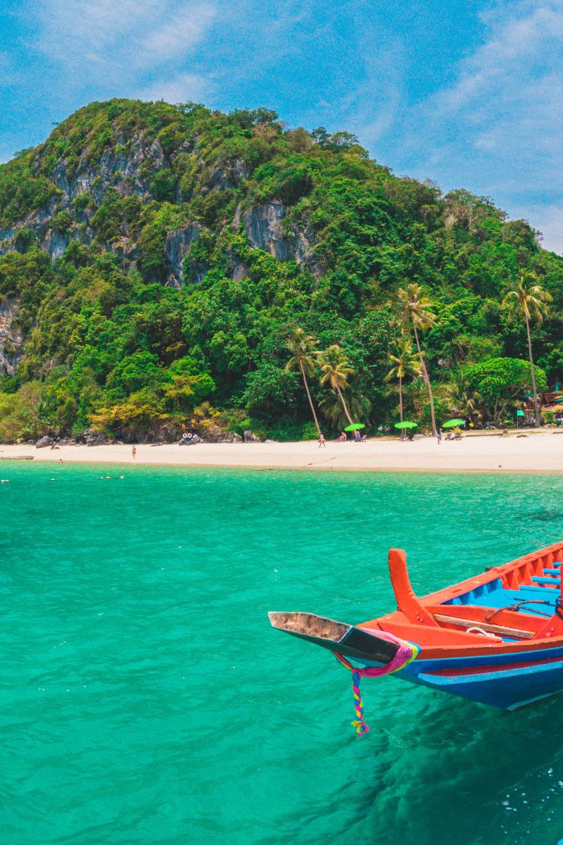 Colorful boat on clear blue water with a tropical island in the background